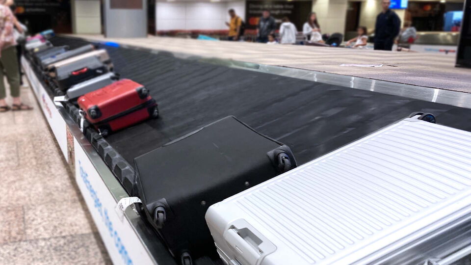 A baggage carousel at the airport transports various suitcases and pieces of luggage on the conveyor belt