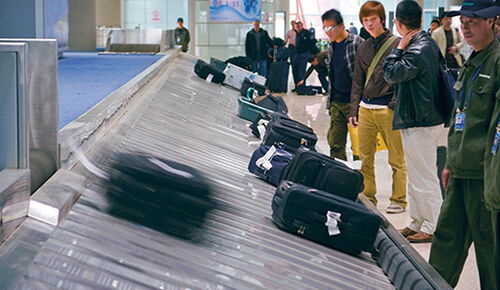 Passengers waiting at the baggage carousel to pick up their luggage