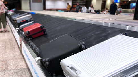 A baggage carousel at the airport transports various suitcases and pieces of luggage on the conveyor belt